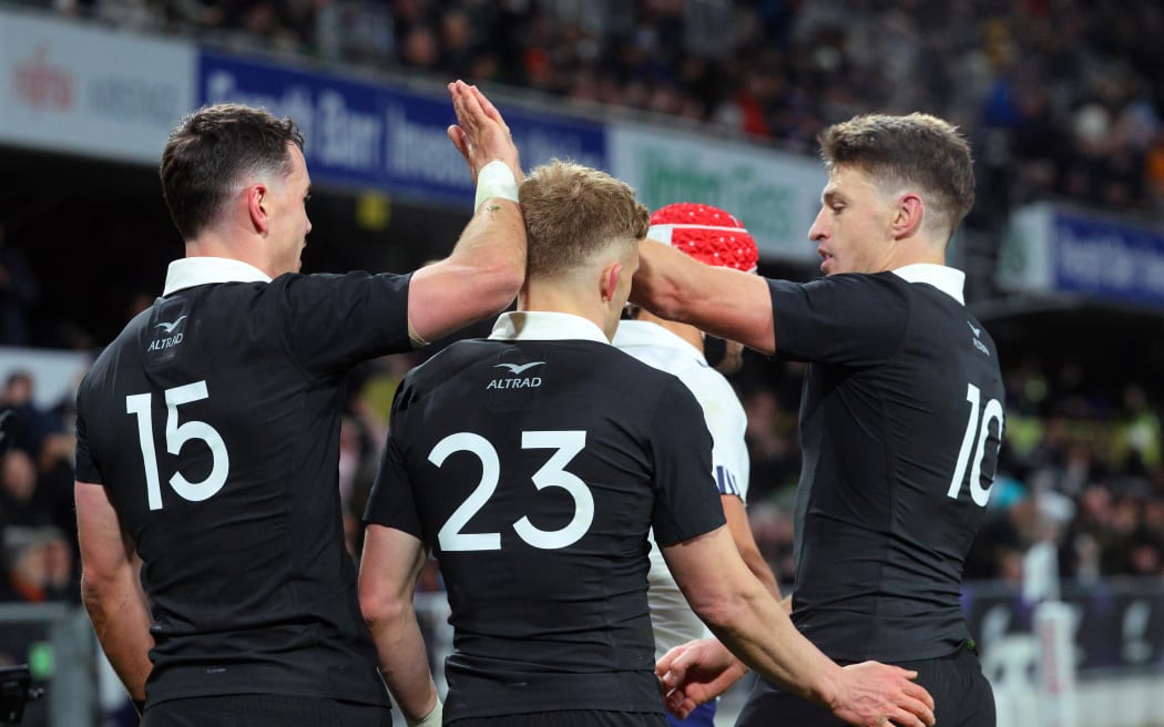 Will Jordan celebrates his try with Damian McKenzie and Beauden Barrett.