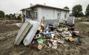 Debris piled up in front of a damaged house in Wairoa