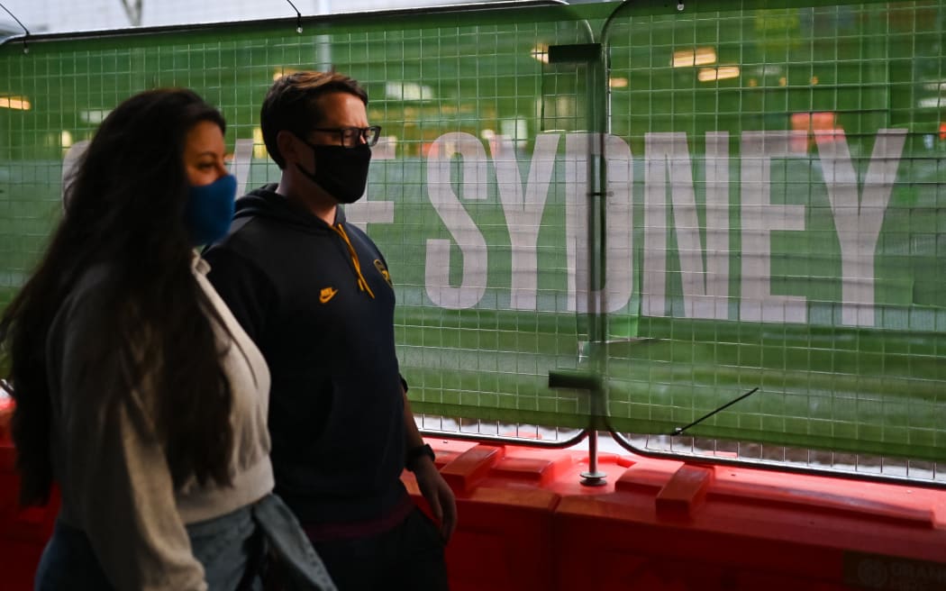 People wearing masks walk in the partially empty street during the first day of lockdown in Sydney, Australia, Saturday, June 26, 2021.