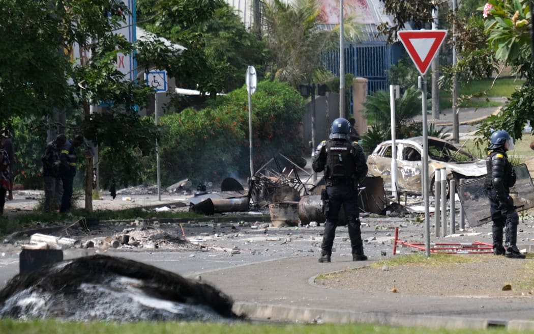 French gendarme officers guard the entrance of the Vallee-du-Tir district, in Noumea on May 14, 2024, amid protests linked to a debate on a constitutional bill aimed at enlarging the electorate for upcoming elections of the overseas French territory of New Caledonia. After scenes of violence of "great intensity" including burned vehicles, looted stores and clashes between demonstrators and the police, a curfew was decreed in Noumea, 17,000 kilometers from Paris, as the independentists of the overseas French territory of New Caledonia oppose a constitutional revision they fear will "further minimize the indigenous Kanak people". (Photo by Theo Rouby / AFP)