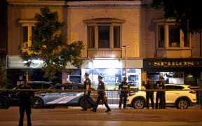 Toronto Police officers walk the scene at Danforth St. at the scene of a shooting in Toronto, Ontario, Canada on July 23, 2018.