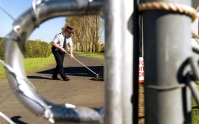 A security guard sweeps the road at the entrance to the Mangere Refugee Centre in Auckland.