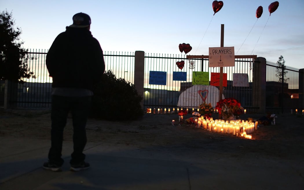 A person looks on at a memorial near the Inland Regional Center.