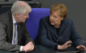 German Interior Minister Horst Seehofer chats with Chancellor Angela Merkel during a session of the German lower house of parliament Bundestag in Berlin on March 4, 2020.