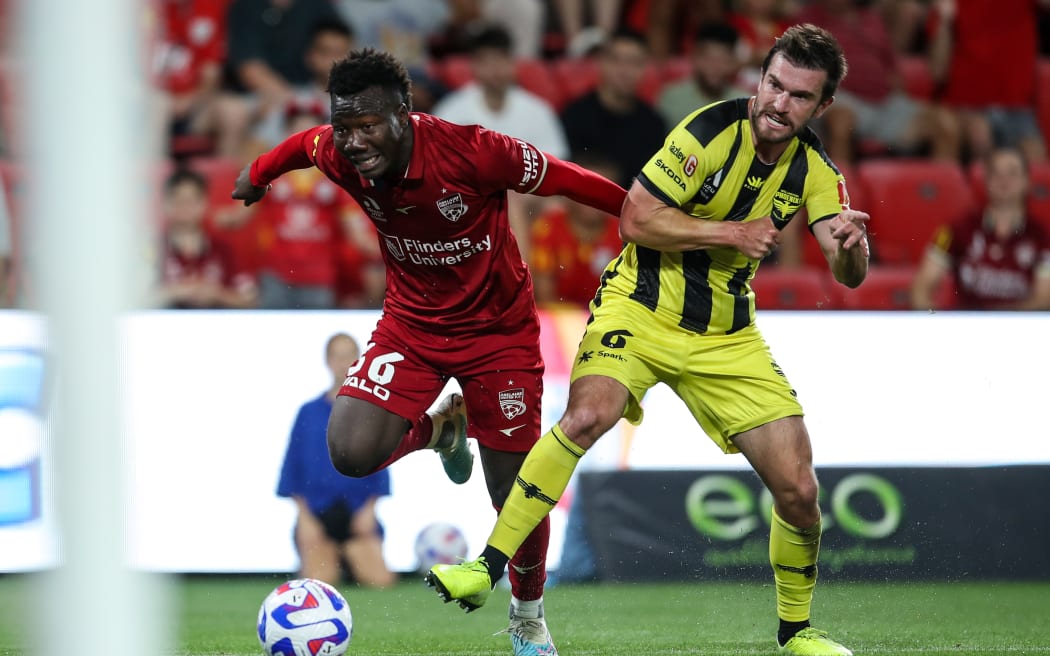 Nestory Irankunda (L) of Adelaide United and Timothy Payne of the Wellington Phoenix compete for possession.
