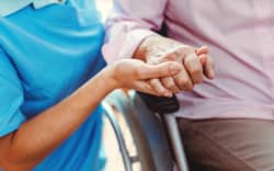 Nurse consoling a senior woman in the nursing home holding her hand in the nursing home