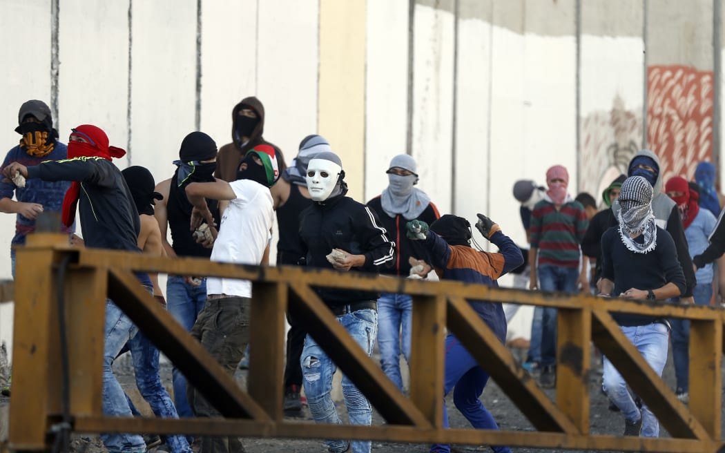 Palestinian protesters throw stones at  Israeli troops next to Israel's controversial separation wall in the Shuafat refugee camp in east Jerusalem.