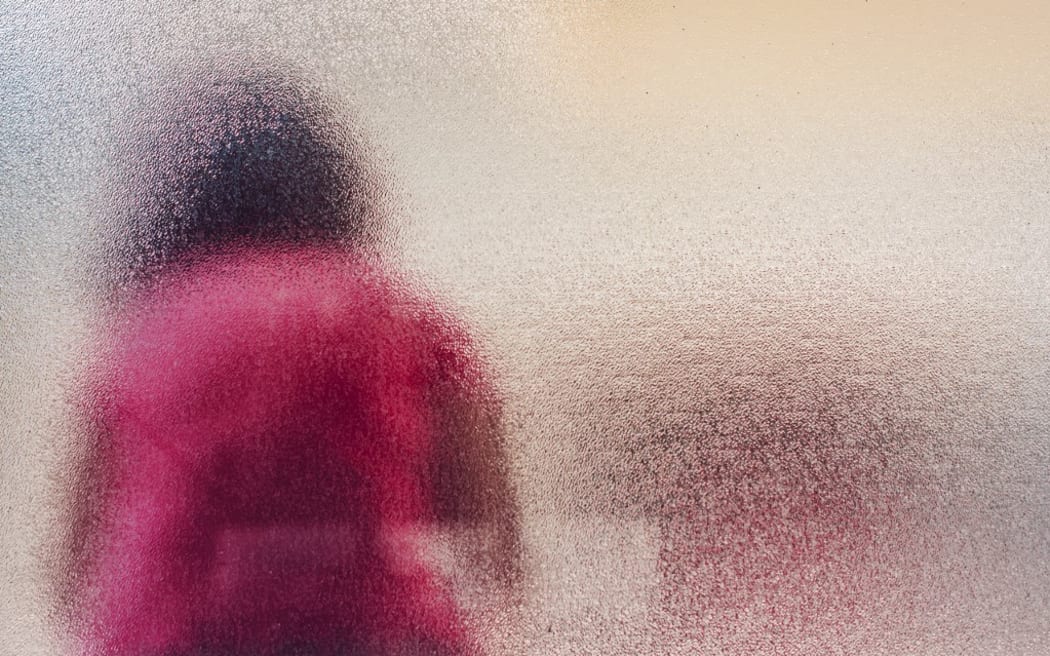 Silhouette of sad girl behind frosted glass. (Photo by IGOR STEVANOVIC / SCIENCE PHOTO / IST / Science Photo Library via AFP)