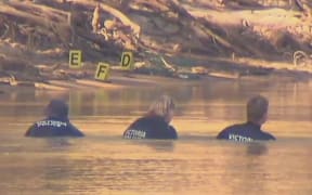 Police divers search the Murray River for the boy.