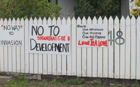 A fence in Whatuwhiwhi with sings on it expressing objection to foreign development.