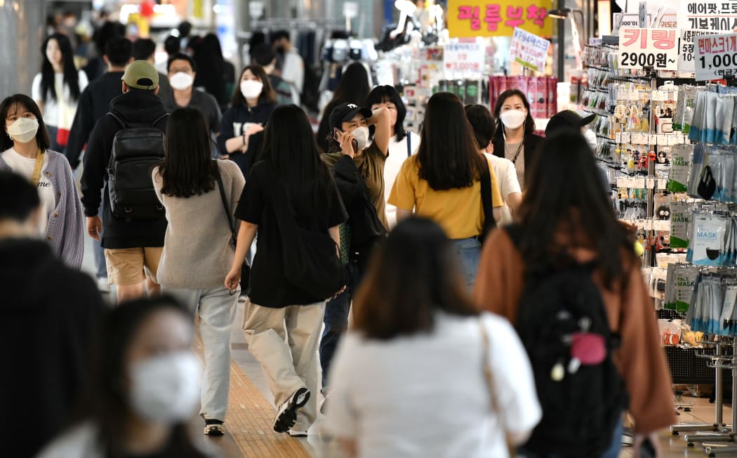 People wearing face masks walk through an underground shopping area in Seoul on May 6, 2020.