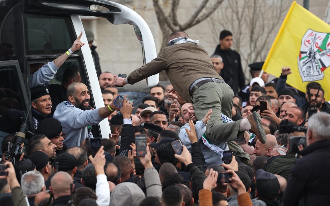 A man jumps to greet a former Palestinian prisoner released by Israel as he and others disembark a Red Cross bus after arriving in Ramallah, in the occupied West Bank on February 1, 2025. The inmates departed from the Israeli prison in the occupied West Bank after three Israeli hostages were handed over by Hamas in Gaza in a fourth such exchange agreed under the ceasefire deal. (Photo by Ahmad GHARABLI / AFP)