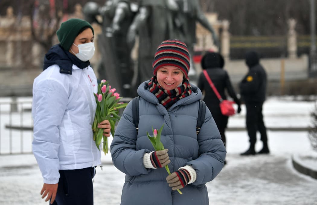 A volunteer gives flowers to a woman in the Muzeon Park on International Women's Day in Moscow, Russia.