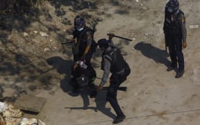 Police beat a protester as they detain him during a demonstration against the military coup in Yangon on 6 March, 2021.