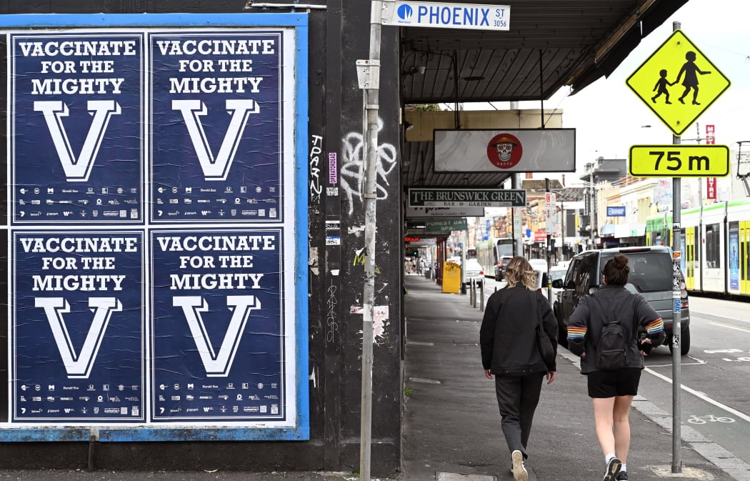 People walk past a sign encouraging people to get vaccinated in Melbourne on August 31, 2021 as the city experiences it's sixth lockdown as it battles an outbreak of the Delta variant of coronavirus.