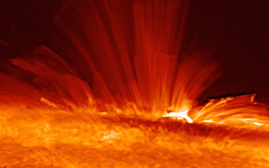 Sunspot with streamers of super-hot, electrically charged gas (plasma) arc from the surface of the Sun, revealing the structure of the solar magnetic field.
