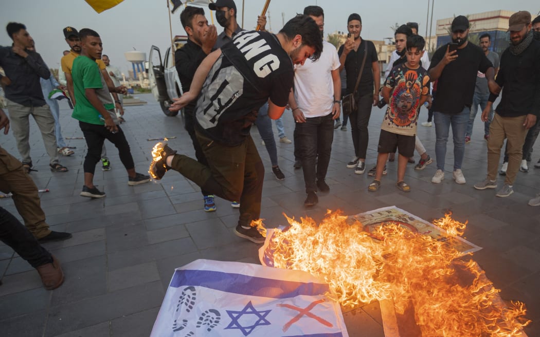 Iraqis burn Israeli flags during a rally held in central Baghdad on October 7, 2023 in support of the Palestinians, after Hamas militants launched a deadly air, land and sea assault into Israel from the Gaza Strip. (Photo by Murtadha Ridha / AFP)