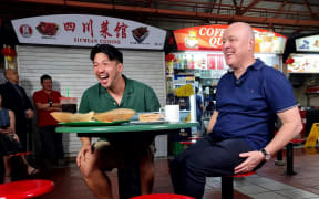Prime Minister Christopher Luxon has a Singaporean street food breakfast with local social media influencer Aiken Chia.