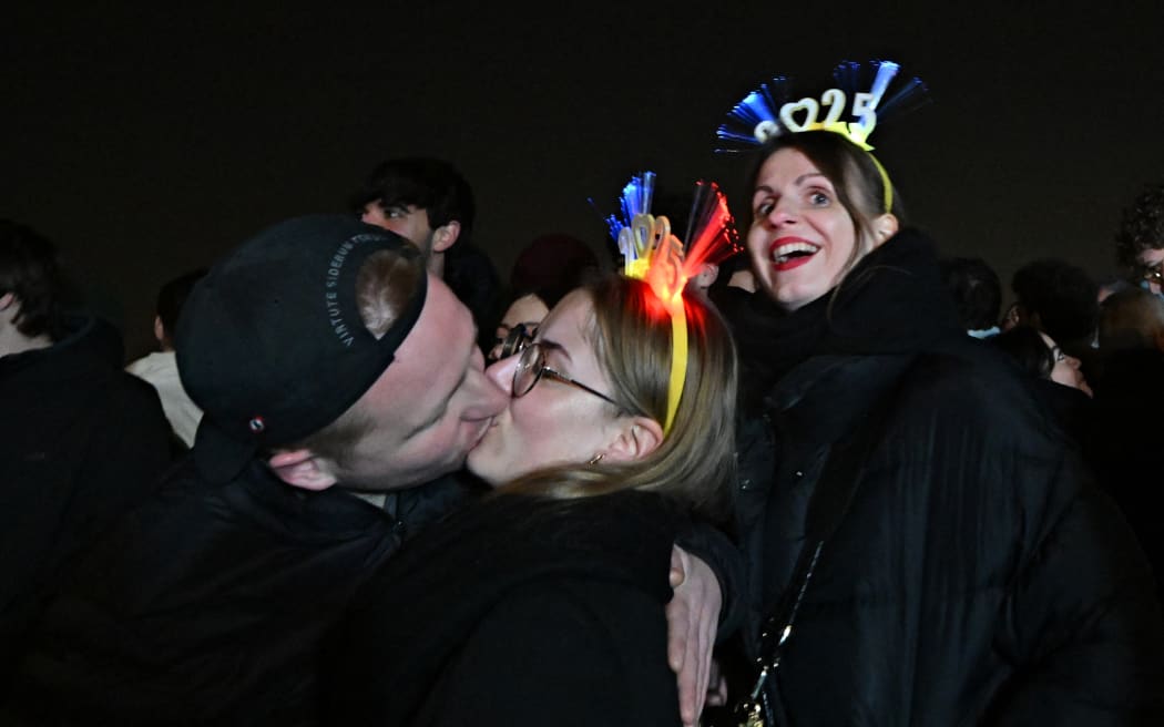 A couple kisses on the Gianicolo Hill, in front of the Garibaldi statue, during the New Year celebration in Rome on January 1, 2025. (Photo by Andreas SOLARO / AFP)