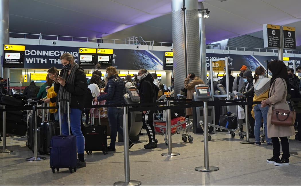 Passengers wearing masks queue at Heathrow Airport in west London on December 21, 2020.