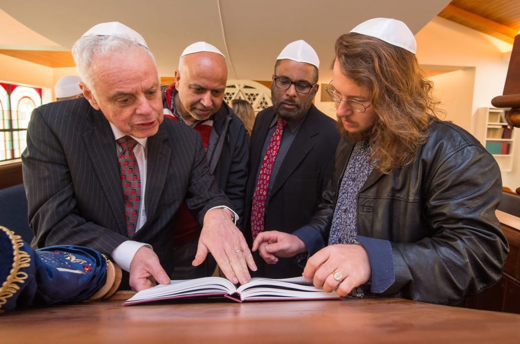New Zealand Jewish Council president Stephen Goodman (front left) and Asher Levi Etherington (front right) show Muslim visitors a Torah at a Christchurch Synagogue.