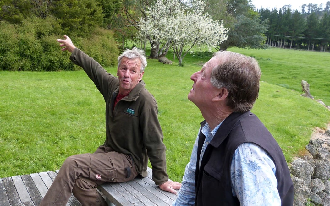 2 men sitting outside with grass behind
