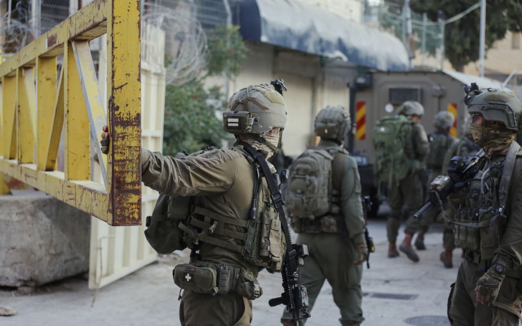 Israeli soldiers patrol a street in Hebron, West Bank, on August 16, 2025. Settlers stormed the old neighborhoods under the protection of the occupation army. (Photo by Mosab Shawer / Middle East Images via AFP)