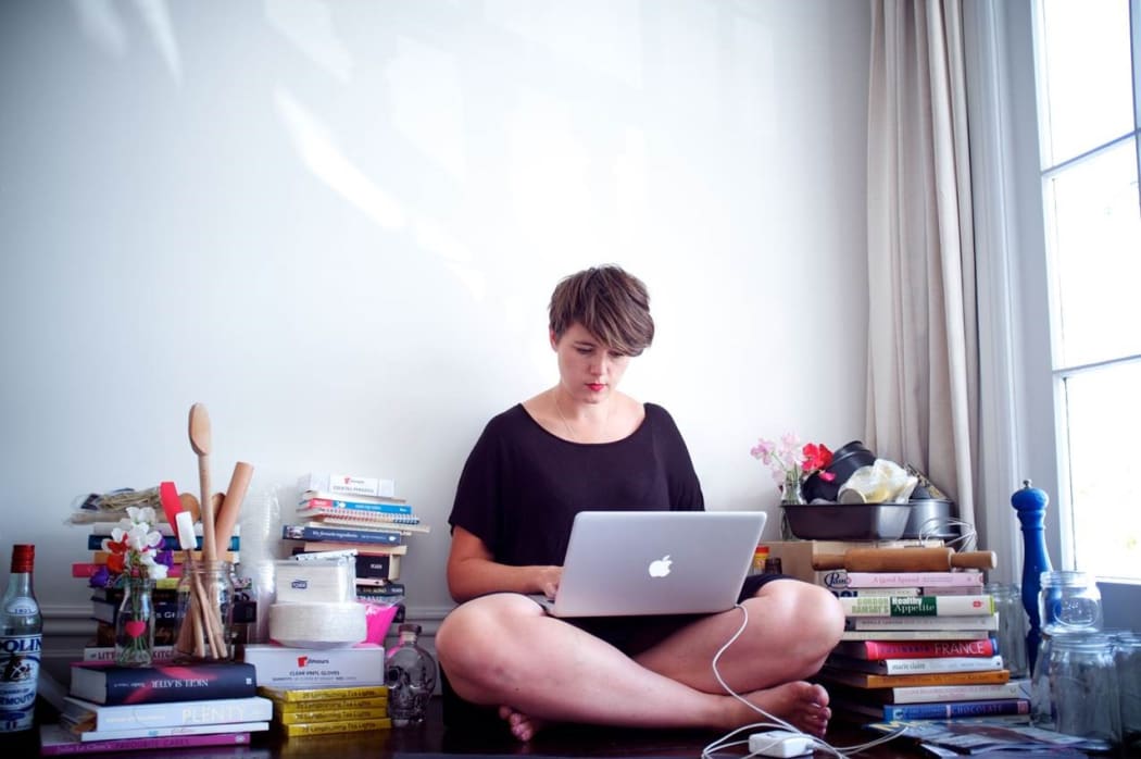 Delaney Mes sitting on the floor, working on her laptop.