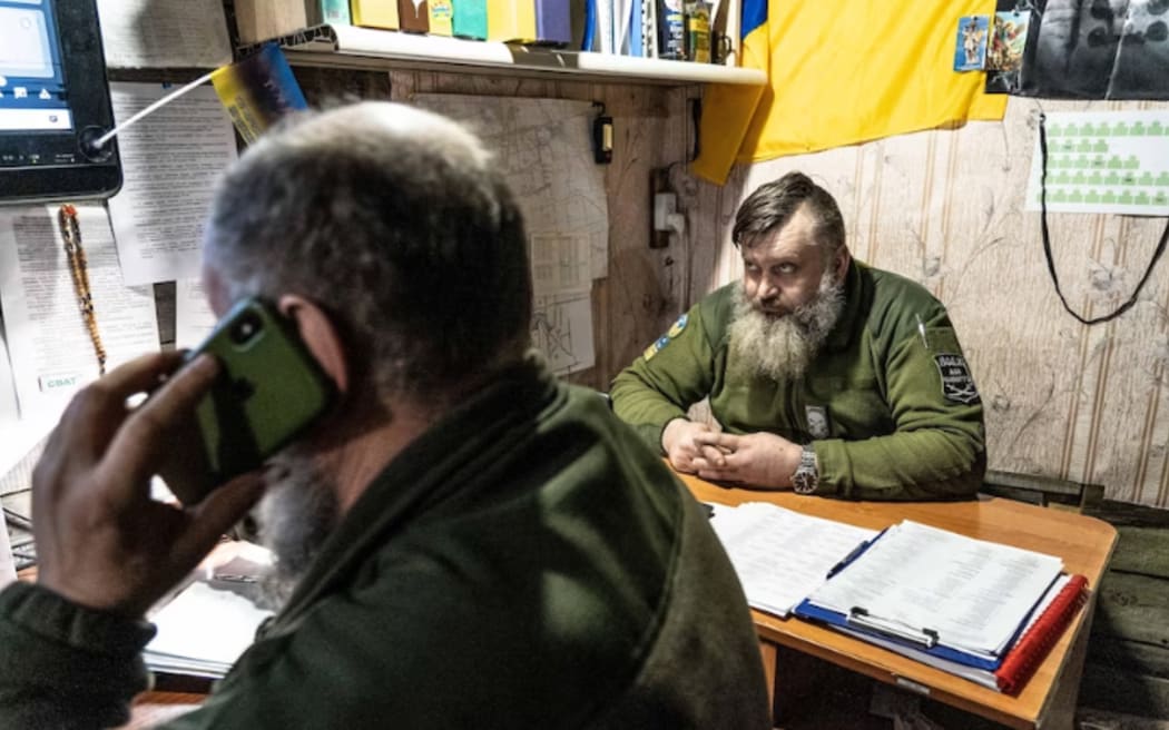 The commander watches a screen showing a live feed from a drone.