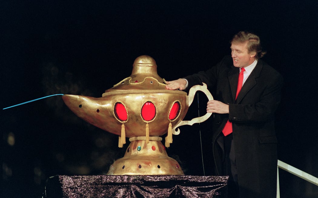Real estate developer Donald J. Trump rubs a "magic lamp" during the opening ceremony for his huge Taj Mahal casino, in Atlantic city, 05 April 1990. Billionaire Donald Trump, who was born in 1946, Queens, New York, has gained notability for his celebrity lifestyle and his real estate successes. (Photo by BILL SWERSEY / AFP)