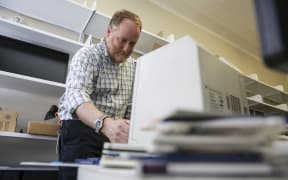 Mick Crouch works with an old-technology floppy disk reader as he preserves New Zealand’s archives