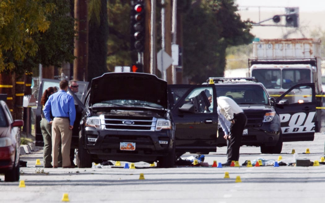 Investigators look at the vehicle involved in a shootout between police and two suspects in San Bernardino, California.