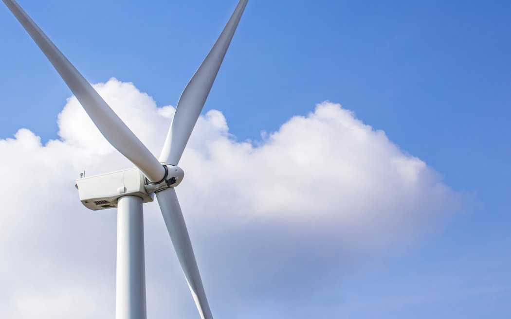 Close up of wind turbine against clouds and blue sky.