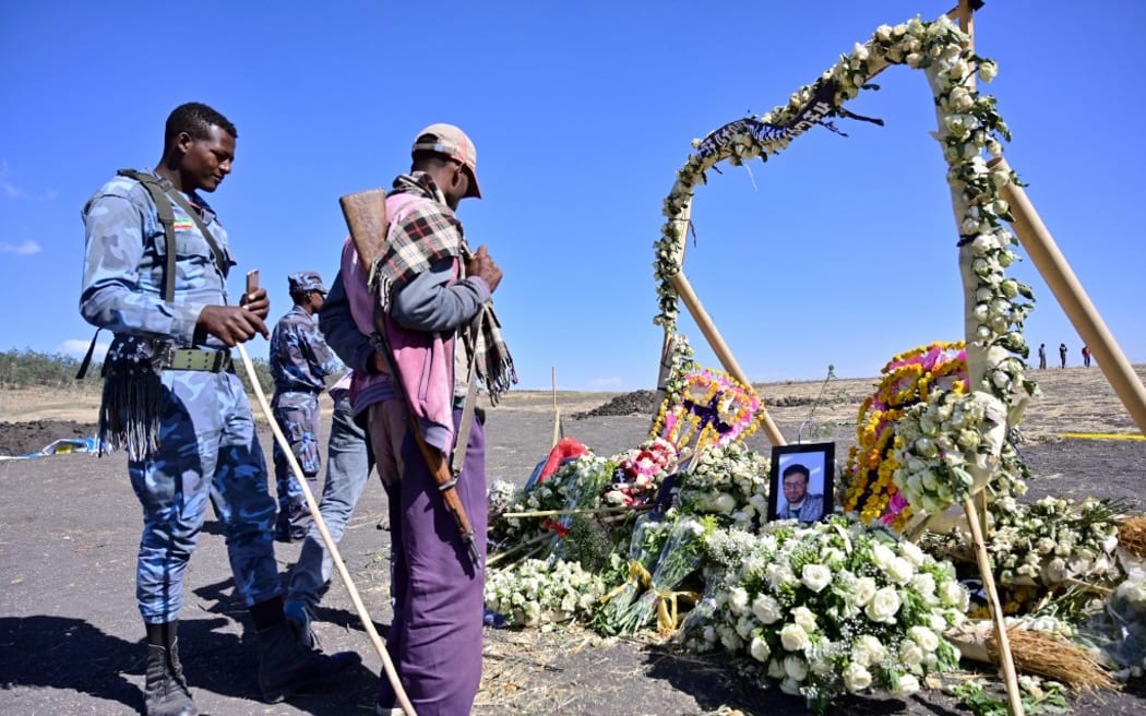 An ethiopian federal policeman and an Oromo tribesman look at a memorial to victims at the crash site of an Ethiopian airways operated Boeing 737 MAX aircraft on March 16, 2019  in Oromia region. -