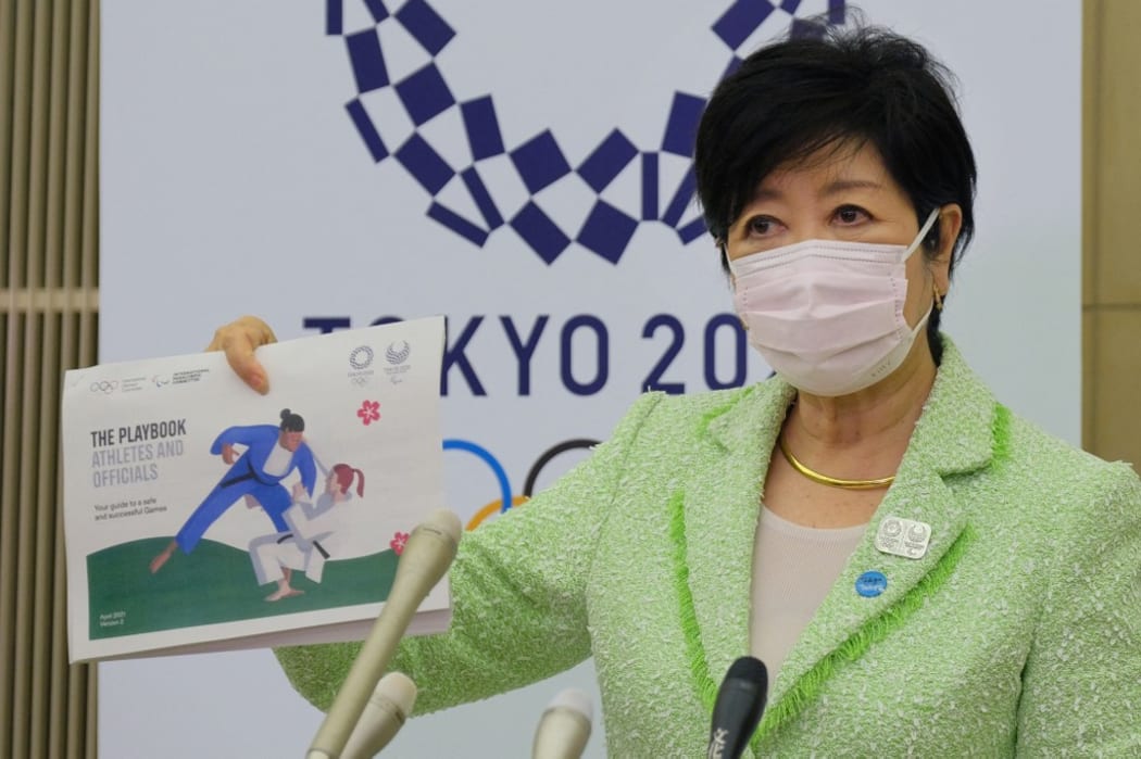 Tokyo Governor Yuriko Koike shows the Tokyo 2020 Olympics playbook while speaking to reporters after a five-party meeting via teleconference with the Tokyo 2020 Organising Committee, Government of Japan, International Olympic Committee and the International Paralympic Committee.