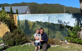 Artist Hana Carpenter and her son in front of the mural of the hills.
