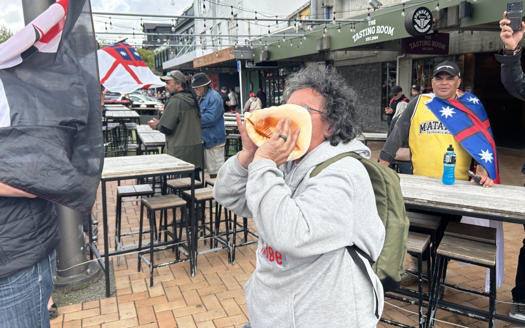 Wahine blows the Pūtātara as the hikoi marches through Courtney Place