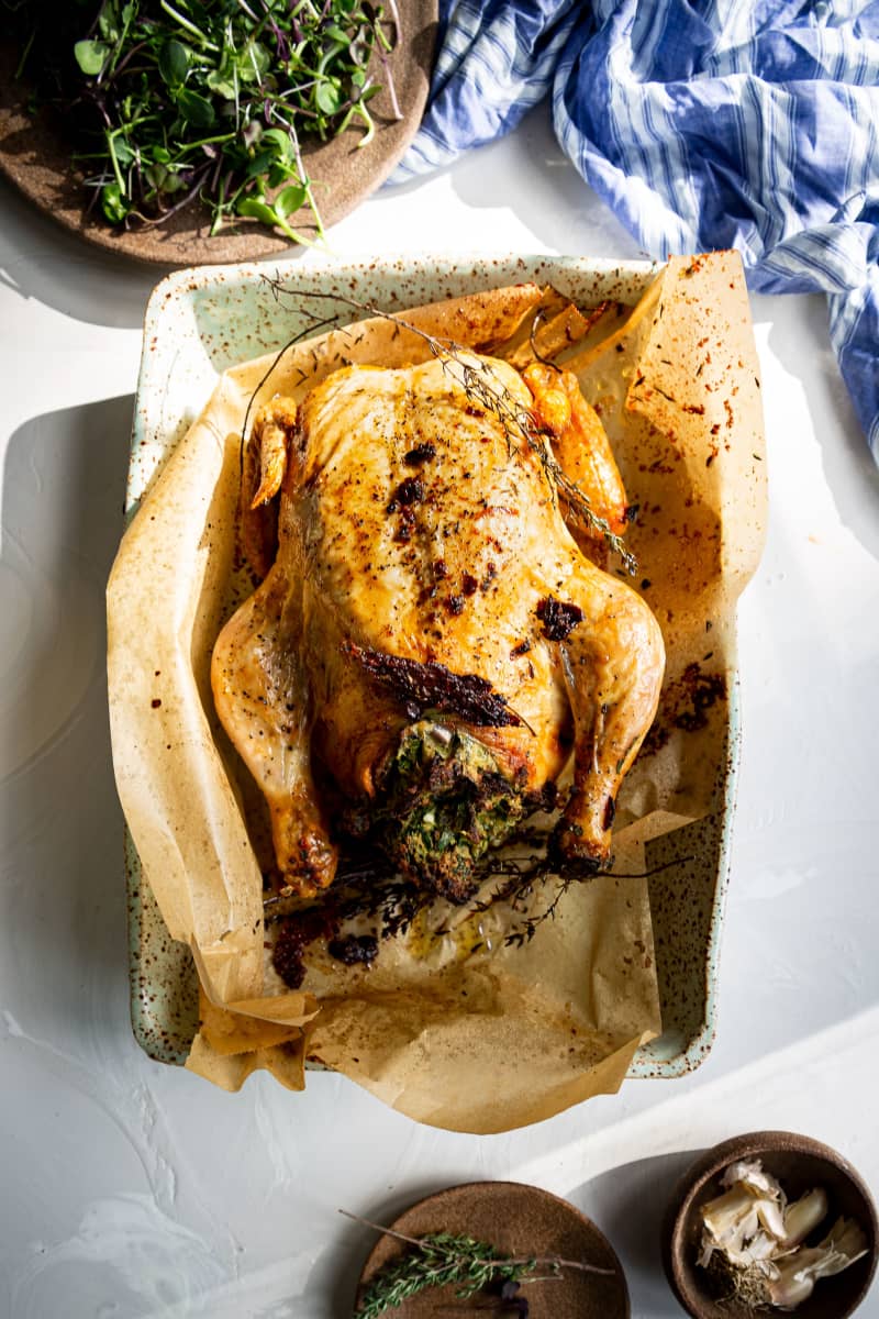 An image of a roast chicken with green stuffing.