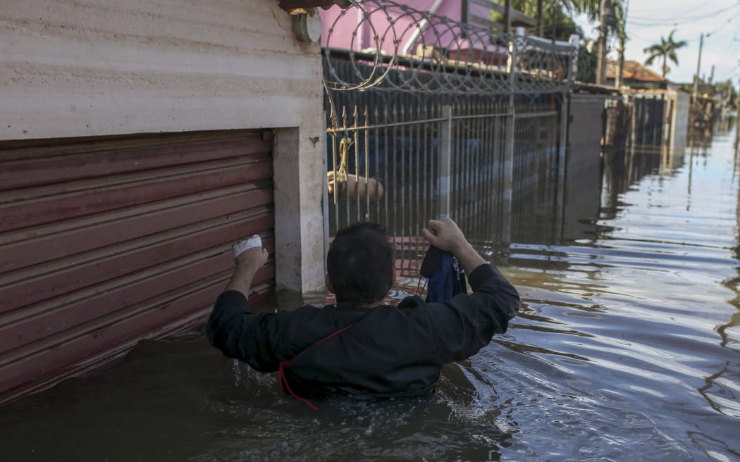 A man returns to his flooded home to retrieve winter clothes in the Rio Branco neighborhood in Canoas, Rio Grande do Sul state, Brazil, on May 17, 2024. More than 600,000 people have been displaced by the heavy rain, flooding and mudslides that have ravaged the south of the state of Rio Grande do Sul for around two weeks. (Photo by Anselmo Cunha / AFP)
