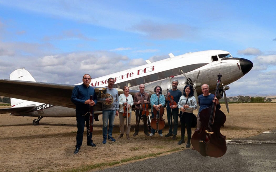 Mark Oremland and musician friends stand next to his DC3 plane.