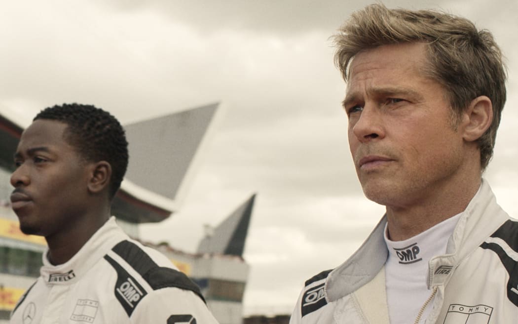 A still from the movie F1: The Movie. Two drivers stare dramatically into the distance wearing specialised white suits.