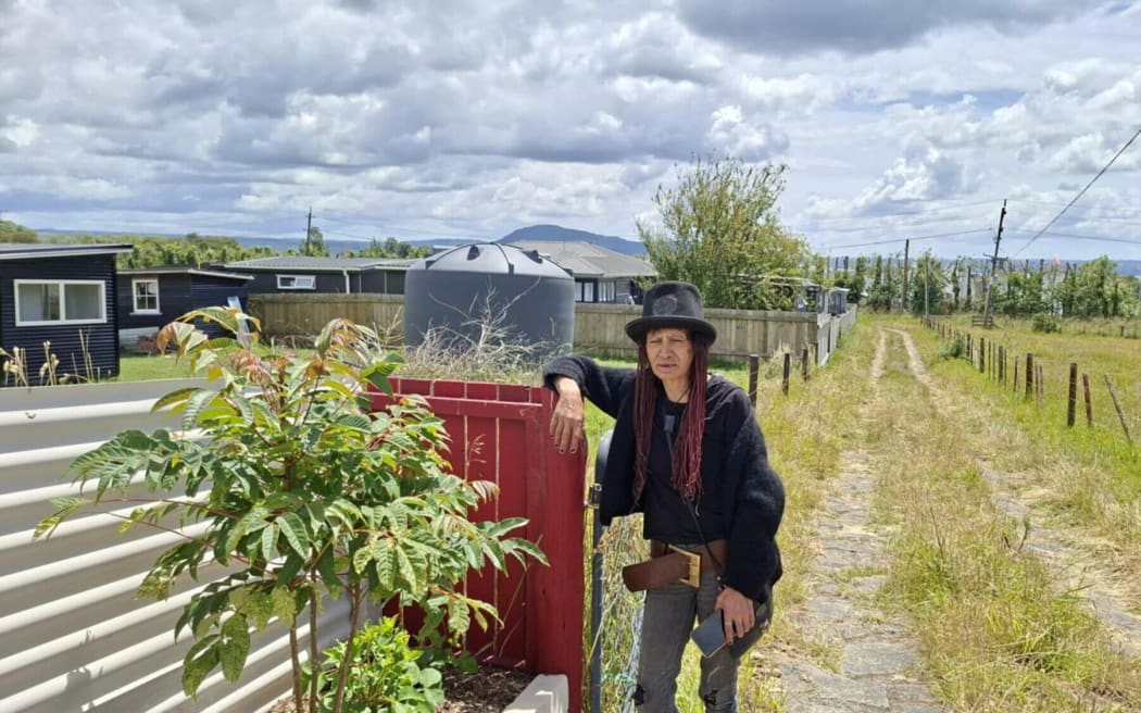 Lauren Fraser at the gate to her property, with the Puwhakamua programme residence behind her.