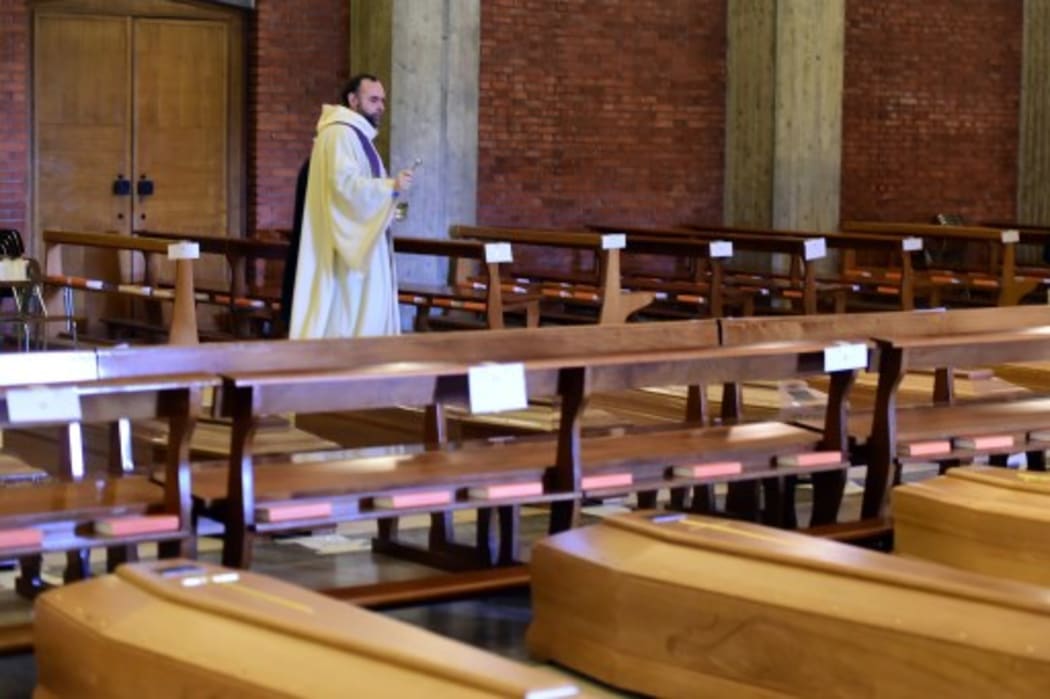 Priest Don Marcello blesses the coffins lined up in the church of San Giuseppe, waiting to be brought to the crematorium by the Italian military on March 28, 2020 in Seriate, Italy.