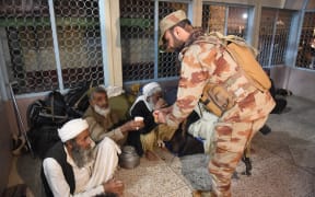 A soldier (R) hands out tea to freed train passengers gathered at the Mach railway station, which has been turned into a makeshift hospital, after Pakistani security forces freed nearly 80 passengers following a security operation against armed militants who ambushed the train in the remote mountainous area, in Mach, southwestern Balochistan province on March 11, 2025. Pakistani troops freed dozens of train passengers taken hostage by armed militants of the Baloch Liberation Army (BLA), a separatist group behind rising violence in the province which borders Afghanistan and Iran, after gunmen forced a train to a halt in a remote, mountainous area of Balochistan province in the afternoon of on March 11, 2025.