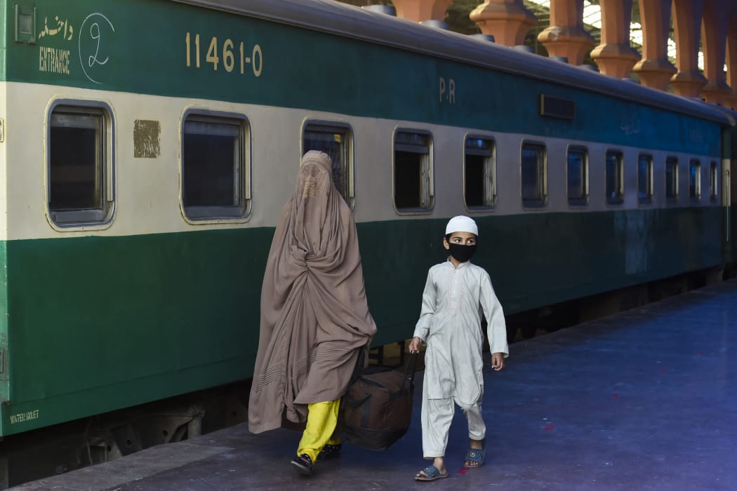 A woman and a child carry their bag as they arrive to board a train to Rawalpindi.