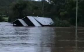 Home being swept away moments after family rescued from roof.