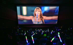 This photo taken on February 3, 2024 shows fans of US singer Taylor Swift, also known as Swifties, cheering as they watch concert film "Taylor Swift: The Eras Tour" at a cinema in Beijing. Waving glow sticks, and sporting sequin dresses and friendship bracelets, Chinese fans of American pop sensation Taylor Swift turn a normally-quiet Beijing cinema into a raucous celebration of their favourite singer. (Photo by Jade GAO / AFP) / To go with AFP story "China-entertainment-music-Swift-fans", SCENE by Luna LIN (STF)