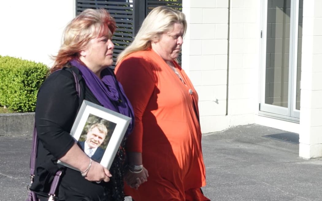 Anna Osborne (left), arrives for the meeting carrying a picture of her husband Milton who died in the mine.