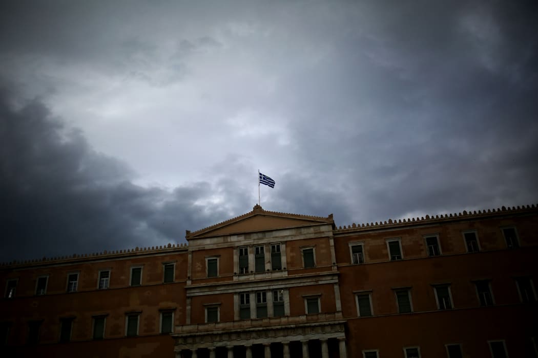 A Greek flag waves at the top of the Greek Parliament.