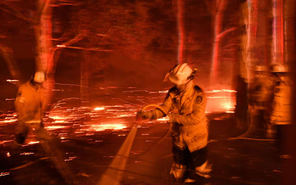 Firefighters hose down the area as they battle against bushfires around the town of Nowra in the Australian state of New South Wales on December 31, 2019.